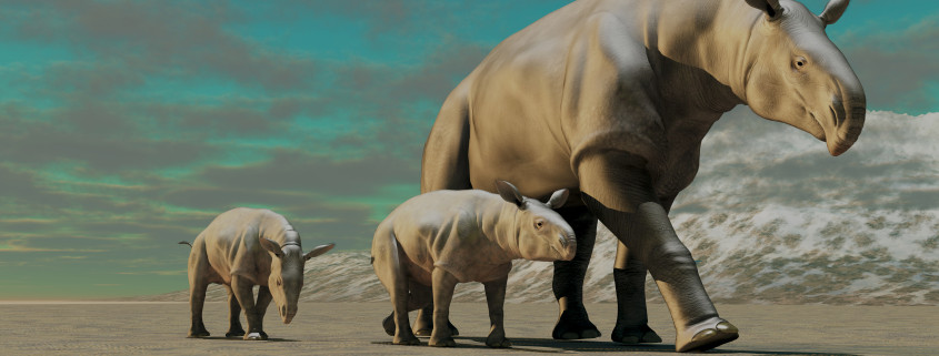 A rhinoceros-like Paraceratherium mother with two twin calves walks along a stony desert in the Oilgocene Era.
