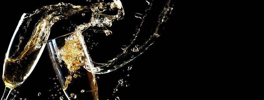 Glasses of champagne with splash, on black background