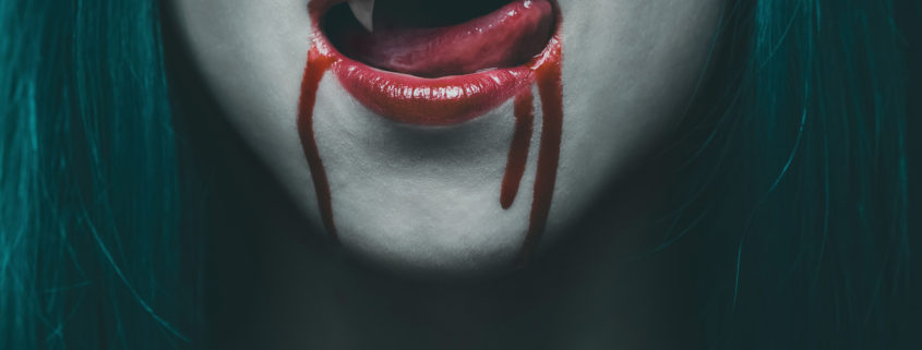 Sensual female vampire lips in blood, close-up image. Halloween or horror theme