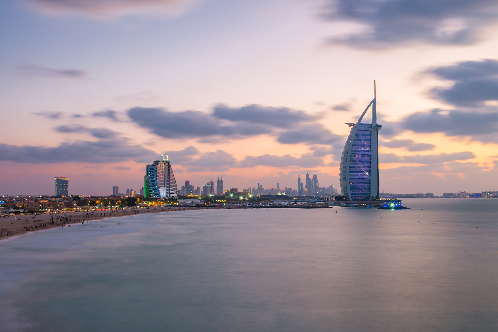 View of the illuminated Burj Al Arab and Jumeirah Beach Hotel at the sunset. View from the Jumeirah beach opposite side, Dubai. Burj Al Arab is a luxury 7 stars hotel built on an artificial island.