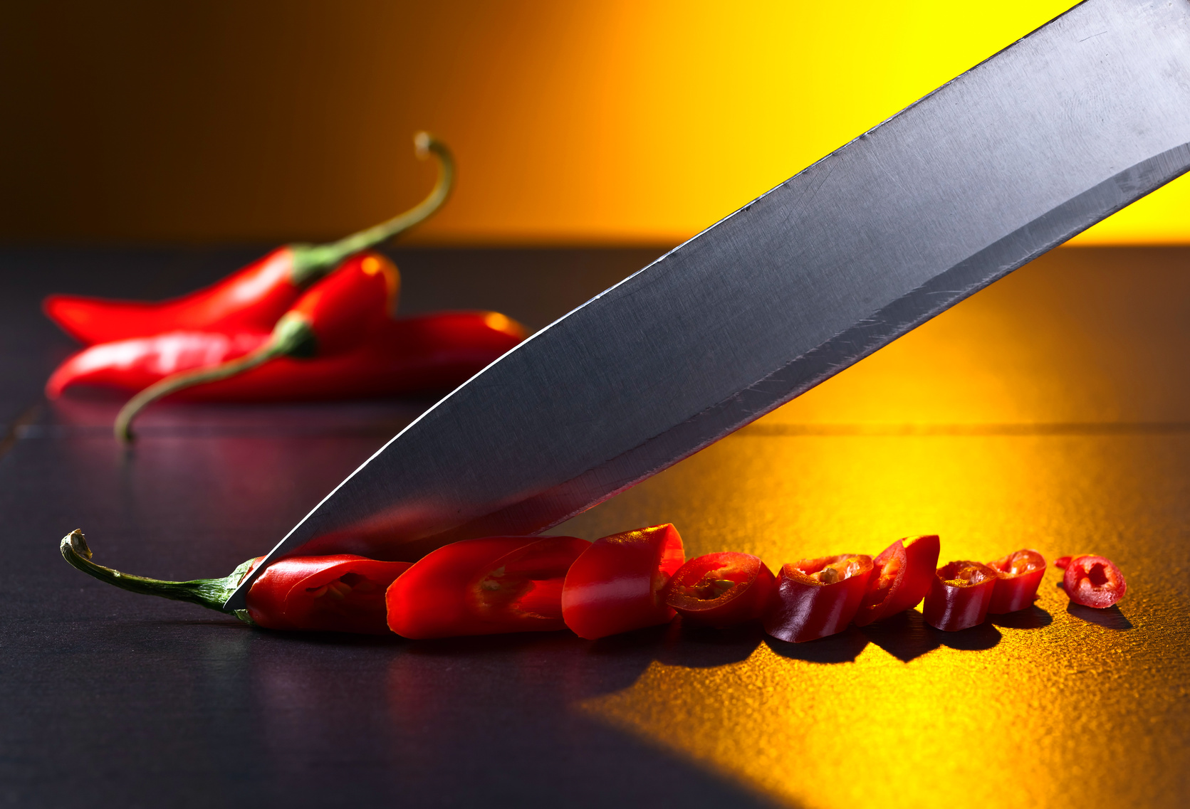 Knife and red chilli pepper on black table