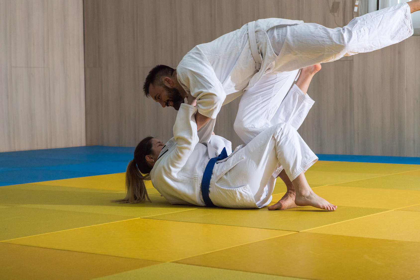 Young woman and man judo fighters in sport hall