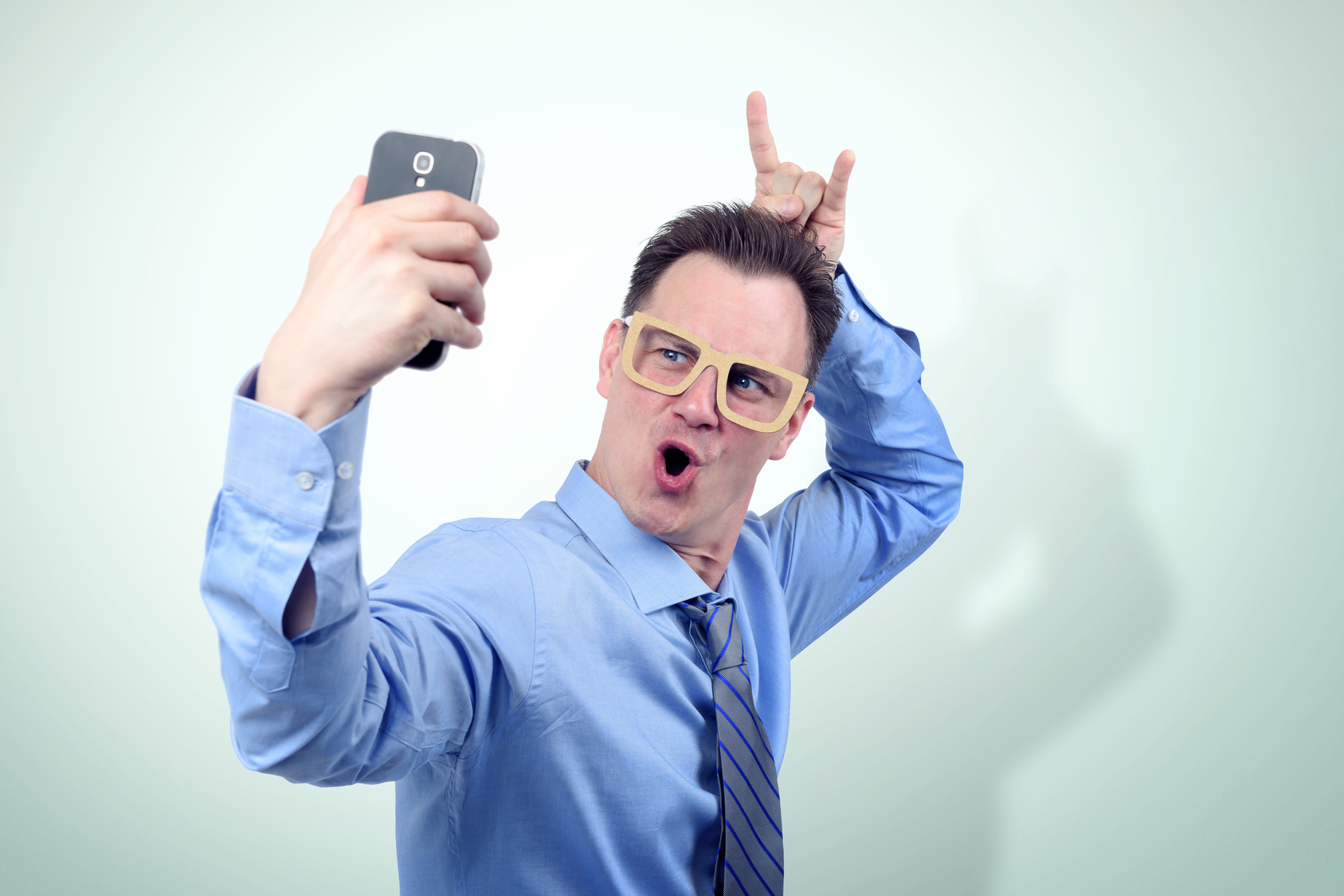 Cool man in funny cardboard glasses makes a smartphone selfie